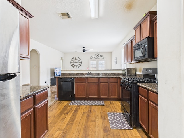9439 Amethyst Glen Dr, Rosharon, TX 77583 - kitchen featuring black appliances, a peninsula, light wood-style flooring, a ceiling fan, and arched walkways