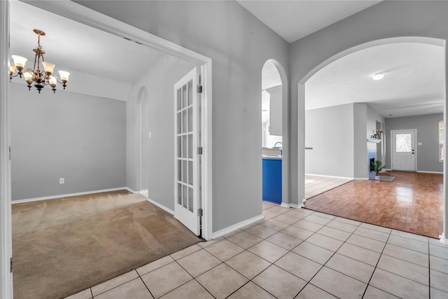 20607 Dademount Ct, Richmond, TX 77407 - spare room featuring arched walkways, a chandelier, light tile patterned floors, and light colored carpet