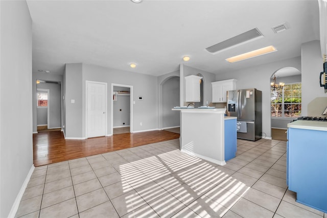 20607 Dademount Ct, Richmond, TX 77407 - kitchen with stainless steel fridge with ice dispenser, light tile patterned floors, healthy amount of natural light, and arched walkways