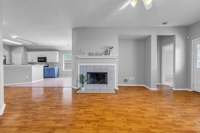 20607 Dademount Ct, Richmond, TX 77407 - unfurnished living room with a tiled fireplace, light wood finished floors, and ceiling fan