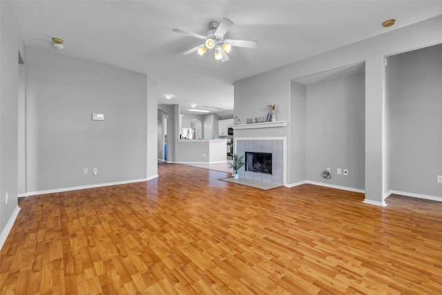 20607 Dademount Ct, Richmond, TX 77407 - unfurnished living room with ceiling fan, light wood-style floors, and a tiled fireplace