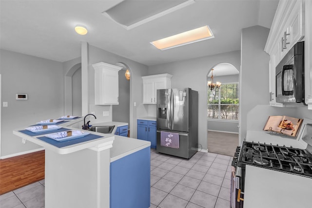 20607 Dademount Ct, Richmond, TX 77407 - kitchen featuring stainless steel fridge, range with gas cooktop, light tile patterned floors, white cabinets, and arched walkways