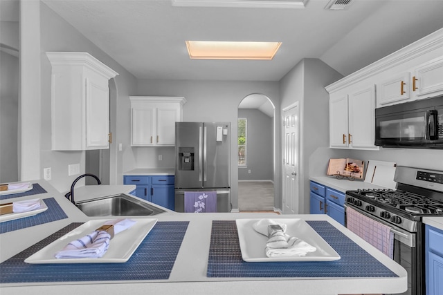 20607 Dademount Ct, Richmond, TX 77407 - kitchen featuring appliances with stainless steel finishes, white cabinetry, blue cabinetry, arched walkways, and light countertops