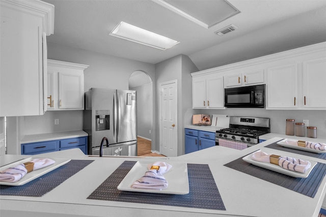 20607 Dademount Ct, Richmond, TX 77407 - kitchen featuring appliances with stainless steel finishes, white cabinets, light countertops, blue cabinetry, and vaulted ceiling