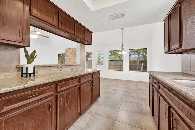 2730 Mesquite Dr, Sugar Land, TX 77479 - kitchen with tasteful backsplash, a ceiling fan, hanging light fixtures, light tile patterned flooring, and light stone countertops
