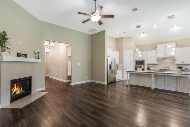 23 N Wheatleigh Dr, Tomball, TX 77375 - living room featuring ceiling fan, vaulted ceiling, dark wood-style floors, and a tile fireplace