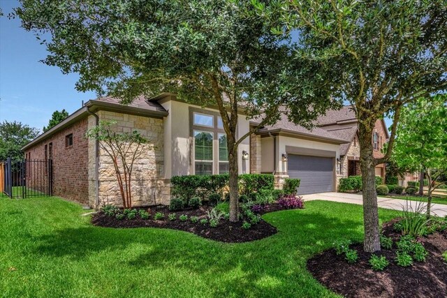 23 N Wheatleigh Dr, Tomball, TX 77375 - view of front facade featuring stone siding, concrete driveway, stucco siding, and a garage