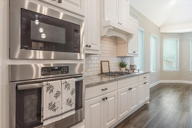 23 N Wheatleigh Dr, Tomball, TX 77375 - kitchen featuring appliances with stainless steel finishes, decorative backsplash, dark wood-type flooring, white cabinetry, and vaulted ceiling