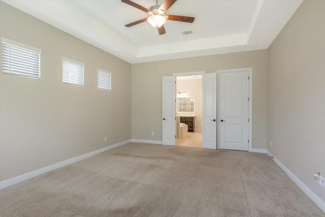 23 N Wheatleigh Dr, Tomball, TX 77375 - unfurnished bedroom with light colored carpet, a raised ceiling, ensuite bathroom, and ceiling fan