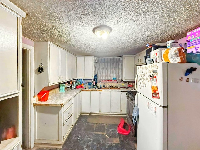 833 N Ave G, Odessa, TX 79763 - kitchen featuring freestanding refrigerator, gas range, a textured ceiling, light countertops, and white cabinetry