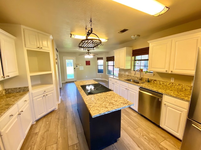 328 Mcguire Rd, Lufkin, TX 75901 - kitchen with stainless steel appliances, a kitchen island, light wood finished floors, white cabinets, and light stone countertops
