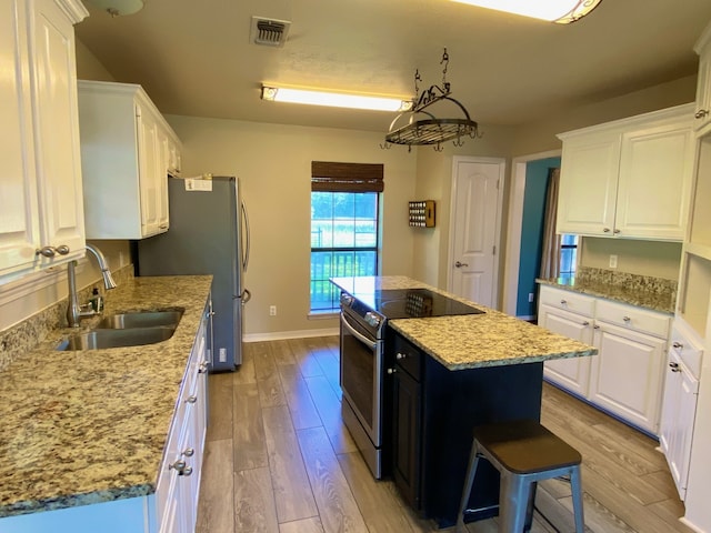 328 Mcguire Rd, Lufkin, TX 75901 - kitchen featuring appliances with stainless steel finishes, light wood-style floors, a center island, white cabinetry, and light stone countertops