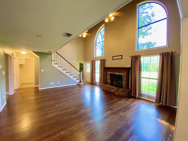 328 Mcguire Rd, Lufkin, TX 75901 - unfurnished living room featuring stairway, wood finished floors, a brick fireplace, and a towering ceiling