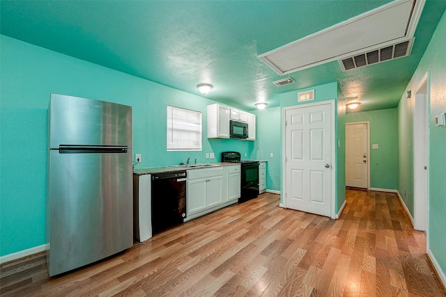 3938 King St, Houston, TX 77026 - kitchen featuring black appliances, white cabinets, light wood-style flooring, light countertops, and a textured ceiling
