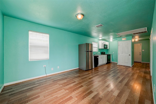 3938 King St, Houston, TX 77026 - kitchen featuring black appliances, white cabinets, wood finished floors, and a textured ceiling