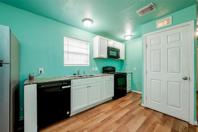 3938 King St, Houston, TX 77026 - kitchen with black appliances, white cabinetry, light wood-style flooring, light countertops, and a textured ceiling