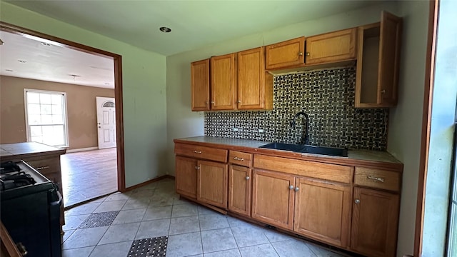 7338 Hurtgen Forest Rd, Houston, TX 77033 - kitchen with gas range, decorative backsplash, brown cabinetry, tile counters, and light tile patterned floors