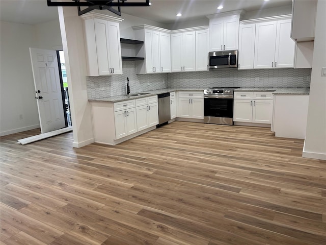 6206 Lyndhurst Dr, Houston, TX 77087 - kitchen with stainless steel appliances, light wood finished floors, decorative backsplash, white cabinets, and recessed lighting