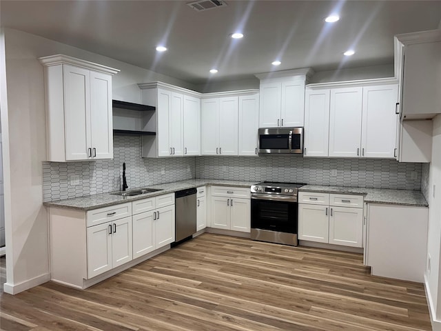 6206 Lyndhurst Dr, Houston, TX 77087 - kitchen with appliances with stainless steel finishes, open shelves, light wood-style floors, white cabinetry, and recessed lighting