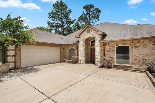 806 Garrett Dr, Magnolia, TX 77354 - french country inspired facade with a shingled roof, brick siding, driveway, and an attached garage