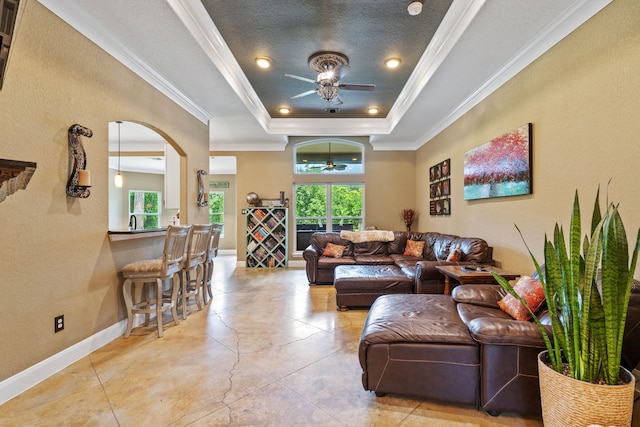 806 Garrett Dr, Magnolia, TX 77354 - living room featuring a ceiling fan, plenty of natural light, a tray ceiling, arched walkways, and ornamental molding