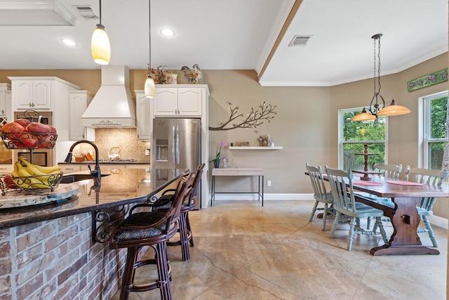 806 Garrett Dr, Magnolia, TX 77354 - kitchen featuring custom range hood, stainless steel fridge with ice dispenser, crown molding, dark stone countertops, and tasteful backsplash