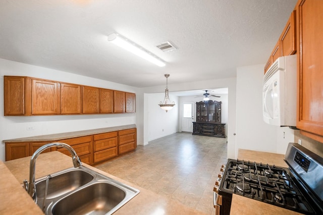2630 Skyview Crest Ct, Houston, TX 77047 - kitchen with stainless steel gas stove, white microwave, brown cabinets, light countertops, and a textured ceiling