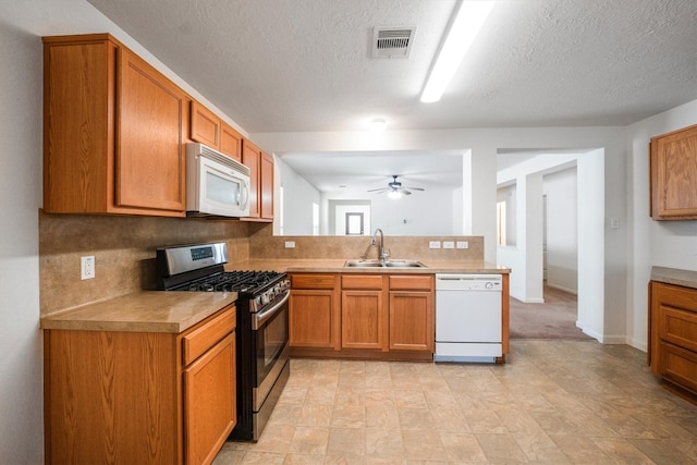 2630 Skyview Crest Ct, Houston, TX 77047 - kitchen featuring white appliances, ceiling fan, a peninsula, tasteful backsplash, and brown cabinets
