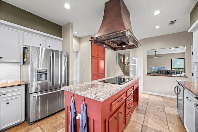 4611 Diamond Springs Dr, Missouri City, TX 77459 - kitchen with stainless steel fridge, ventilation hood, black electric cooktop, ceiling fan, and stone tile floors