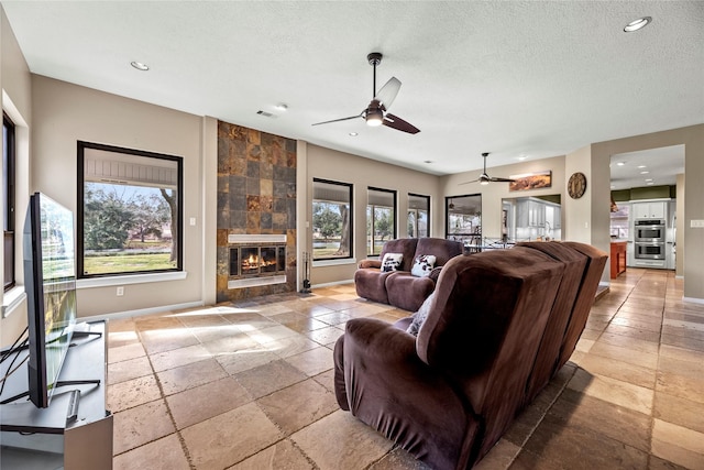 4611 Diamond Springs Dr, Missouri City, TX 77459 - living room featuring stone tile floors, a ceiling fan, a textured ceiling, recessed lighting, and a fireplace