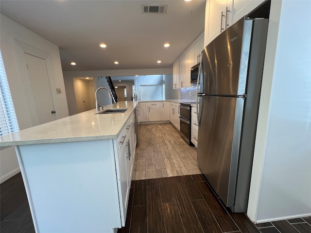 2372 Woodland Park Dr Unit 121, Houston, TX 77077 - kitchen featuring stainless steel appliances, wood finished floors, white cabinetry, recessed lighting, and light stone countertops