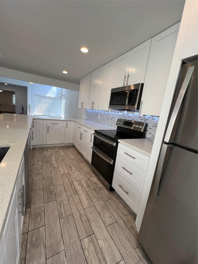 2372 Woodland Park Dr Unit 121, Houston, TX 77077 - kitchen featuring appliances with stainless steel finishes, light wood-style flooring, white cabinets, backsplash, and light stone counters