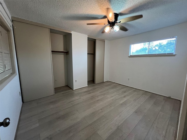 2372 Woodland Park Dr Unit 121, Houston, TX 77077 - unfurnished bedroom with multiple closets, a textured ceiling, light wood-style floors, and ceiling fan