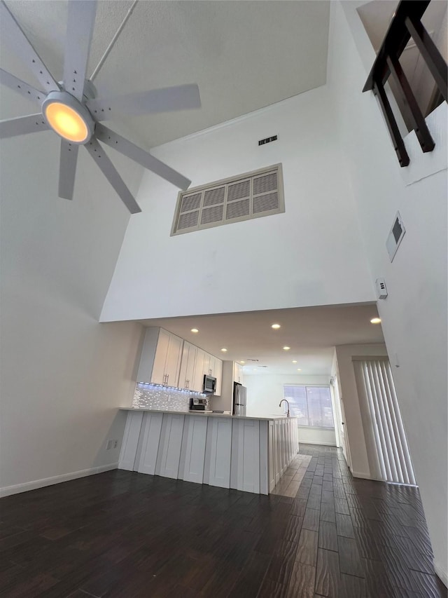 2372 Woodland Park Dr Unit 121, Houston, TX 77077 - kitchen with stainless steel appliances, a towering ceiling, dark wood-style flooring, ceiling fan, and a peninsula