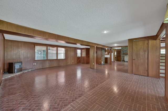 17230 Pioneer Trl, Conroe, TX 77302 - unfurnished living room featuring wooden walls, brick patterned floors, a textured ceiling, and plenty of natural light