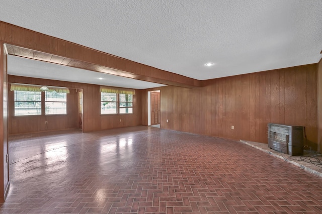 17230 Pioneer Trl, Conroe, TX 77302 - unfurnished room featuring heating unit, wood walls, a textured ceiling, and a wood stove