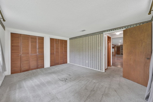 17230 Pioneer Trl, Conroe, TX 77302 - unfurnished bedroom featuring two closets, carpet, and a textured ceiling