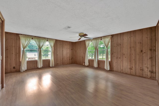 17230 Pioneer Trl, Conroe, TX 77302 - empty room featuring wood finished floors, wooden walls, a textured ceiling, plenty of natural light, and ceiling fan