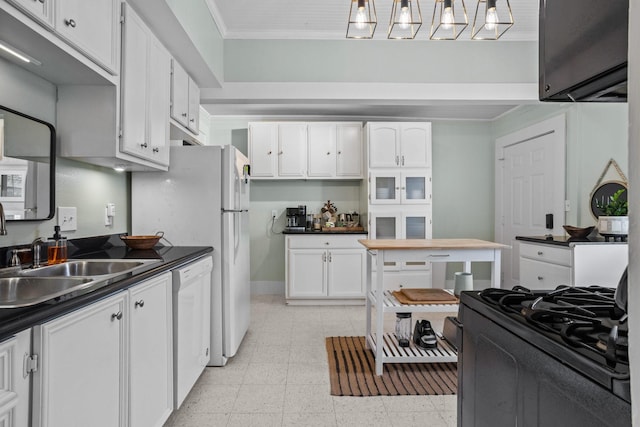 2413 34th St, Galveston, TX 77550 - kitchen featuring dishwasher, dark countertops, white cabinets, stove, and crown molding