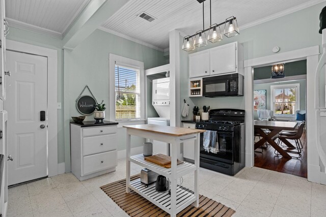 2413 34th St, Galveston, TX 77550 - kitchen with black appliances, stacked washing machine and dryer, plenty of natural light, a chandelier, and ornamental molding