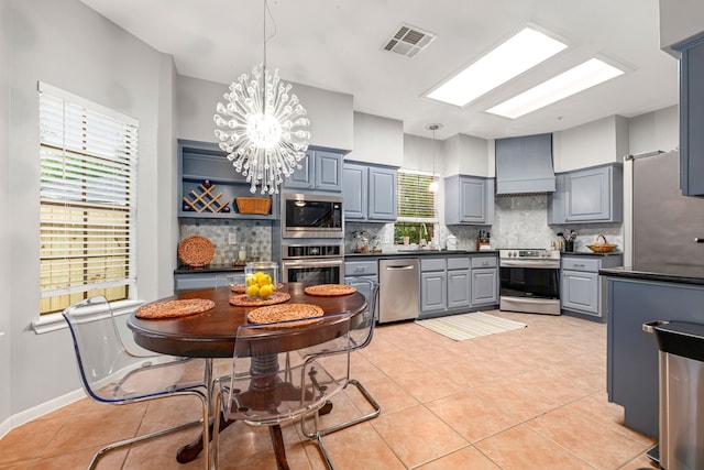 6 Heathstone Pl, The Woodlands, TX 77381 - kitchen featuring stainless steel appliances, custom range hood, dark countertops, gray cabinets, and decorative backsplash