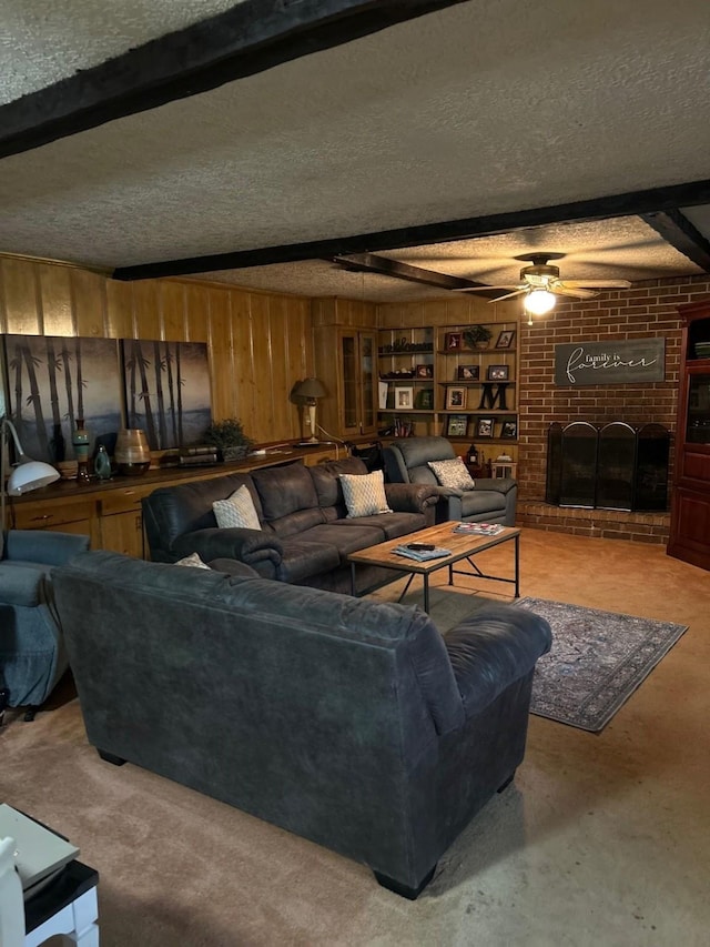 315 N Marsh Dr, Livingston, TX 77351 - living room with a textured ceiling, ceiling fan, wood walls, beam ceiling, and a brick fireplace