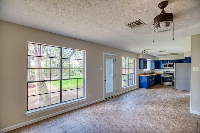 14715 Cobre Valley Dr, Houston, TX 77062 - kitchen with blue cabinets, stainless steel appliances, light countertops, light tile patterned floors, and a textured ceiling