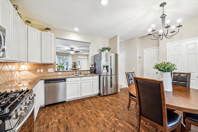 29708 Parliament Hills Dr, Spring, TX 77386 - kitchen with stainless steel appliances, dark wood finished floors, white cabinets, tasteful backsplash, and a chandelier