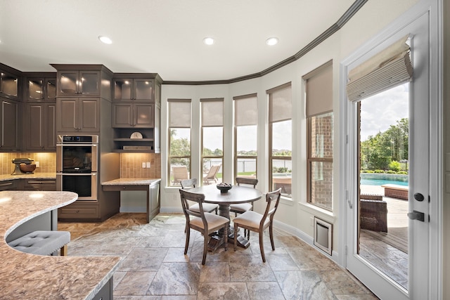 28106 Island Manor Ln, Fulshear, TX 77441 - kitchen featuring stainless steel double oven, backsplash, recessed lighting, stone tile flooring, and crown molding