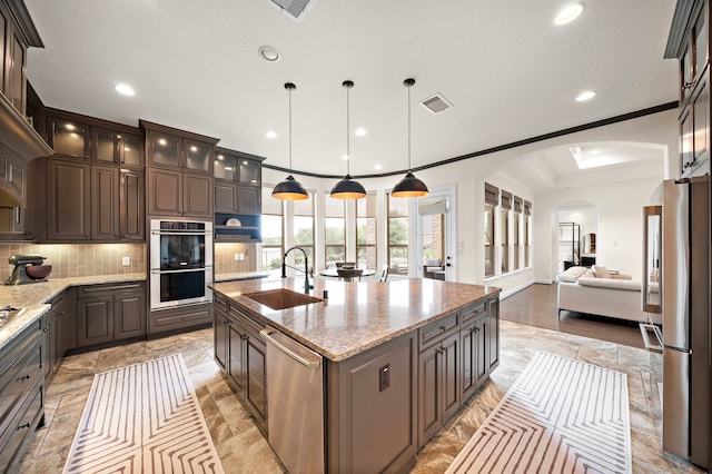 28106 Island Manor Ln, Fulshear, TX 77441 - kitchen with appliances with stainless steel finishes, tasteful backsplash, arched walkways, open floor plan, and dark brown cabinets