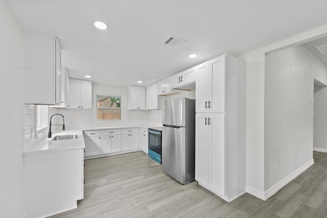 1615 Hiller St, Houston, TX 77015 - kitchen featuring freestanding refrigerator, light wood-style flooring, decorative backsplash, light countertops, and range with electric stovetop