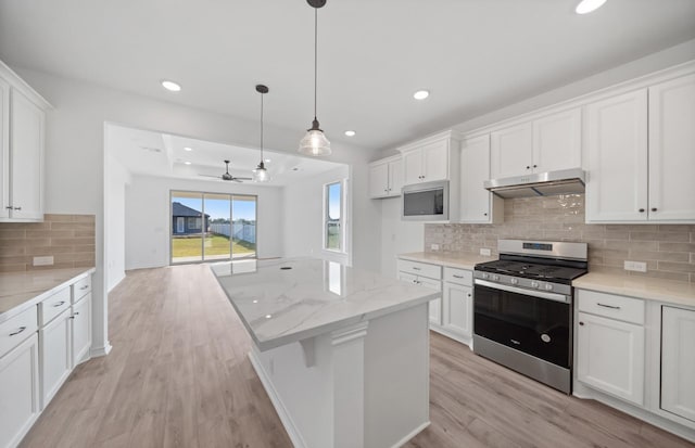 31727 Valor Dr, Fulshear, TX 77441 - kitchen with appliances with stainless steel finishes, under cabinet range hood, light wood finished floors, white cabinetry, and recessed lighting