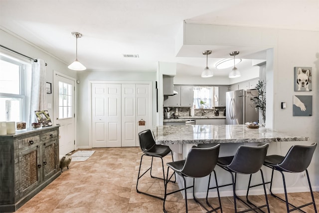 1721 Bowline Rd, Houston, TX 77062 - kitchen featuring freestanding refrigerator, a peninsula, a kitchen breakfast bar, light stone counters, and hanging light fixtures