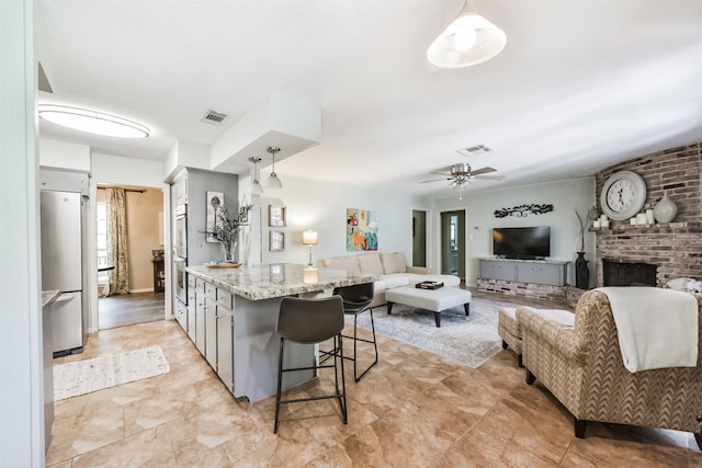 1721 Bowline Rd, Houston, TX 77062 - kitchen with stainless steel appliances, a breakfast bar area, light stone counters, decorative light fixtures, and ceiling fan